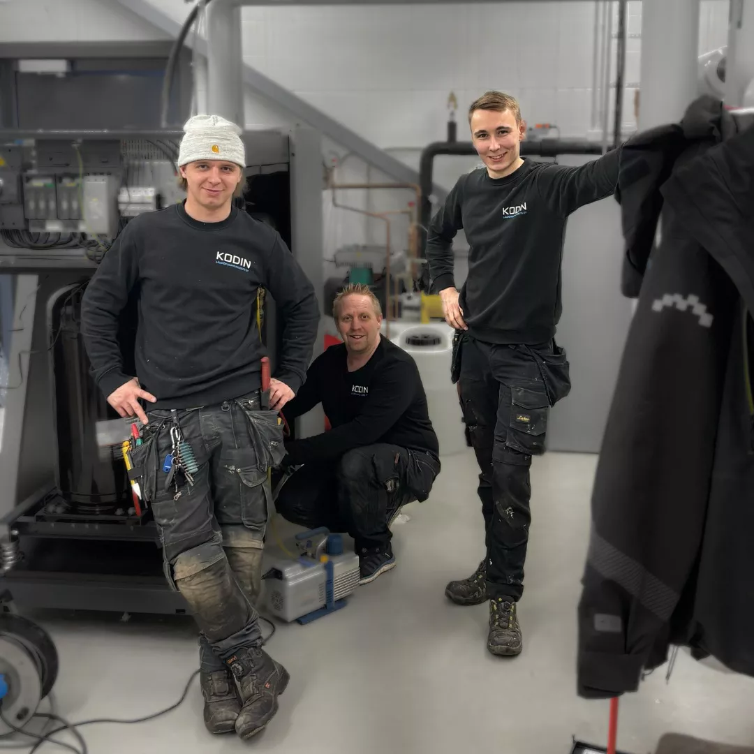 Kolme Vastuu Energian asentajaa mustissa työvaatteissa lämpöpumppuasennuksen äärellä